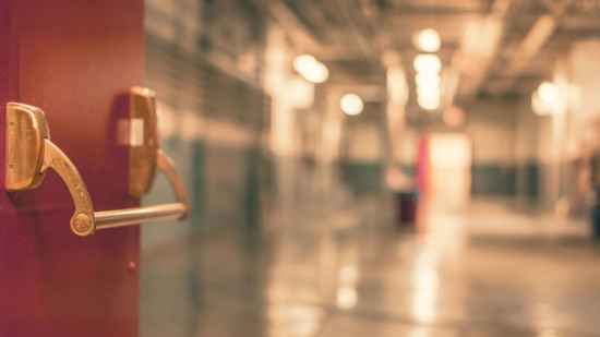 Das Bild zeigt verschwommen eine Krankenhaustür mit Flur